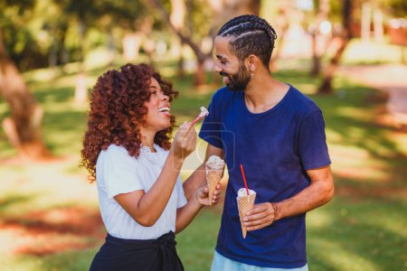 Téléchargez les photos : Couple Valentine manger de la crème glacée dans le parc - en image libre de droit