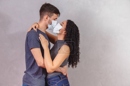 Young millennials couple wearing protective face masks and kissing each other, virus spread prevention and people concept. Valentine couple with mask. Quarantine