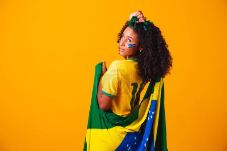 Foto de Abanico brasileño. vistiendo bandera brasileña en un retrato, abanico brasileño celebrando fútbol o partido de fútbol sobre fondo amarillo. Colores de Brasil.Copa del Mundo - Imagen libre de derechos
