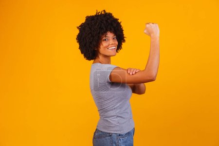 Photo for We can do it. Woman's fist of female power. Woman victim of racism. Abuse at work. The feminine power. Female empowerment. The strength of women. Yellow background. - Royalty Free Image
