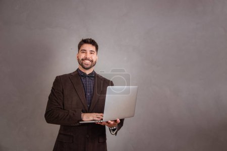 Foto de Hombre guapo trabajando con su portátil sobre fondo gris - Imagen libre de derechos