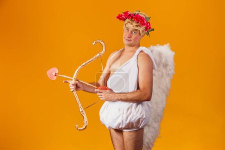 Foto de Concepto de San Valentín. Retrato del Dios del amor - Cupido con arco y flecha sobre fondo amarillo. - Imagen libre de derechos