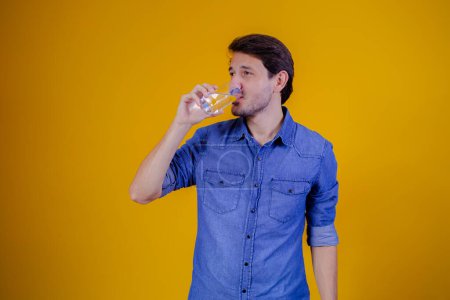 Téléchargez les photos : Homme eau potable en fond jaune. - en image libre de droit