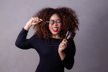 Foto de Afro mujer profesional maquillaje artista celebración maquillaje cepillos. - Imagen libre de derechos