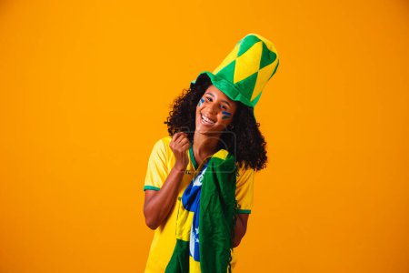 Téléchargez les photos : Un fan brésilien. Fan brésilien célébrant le football ou le match de football sur fond jaune. Couleurs du Brésil. - en image libre de droit