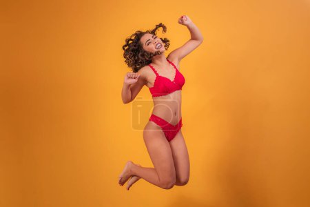 Photo for Afro woman with lingerie jumping over yellow background. - Royalty Free Image
