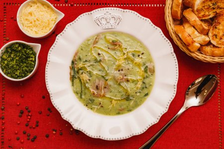 Photo for Delicious broccoli green broth, green broccoli soup, vegetarian, with grated parmesan cheese and parsley, with wooden background and red fabric, Gastronomy, Brazilian winter foods - Royalty Free Image