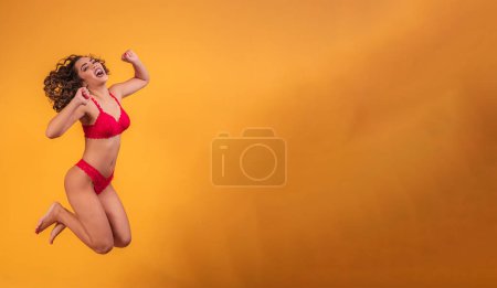 Photo for Afro woman with lingerie jumping over yellow background. - Royalty Free Image