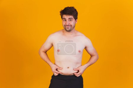 Photo for Man touching his fat belly ( close up). Obese man hand holding excessive belly fat isolated with yellow blackground. reduce belly and shape up healthy stomach muscle. - Royalty Free Image