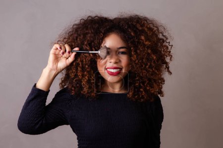 Téléchargez les photos : Afro femme maquilleuse professionnelle tenant des pinceaux de maquillage. - en image libre de droit