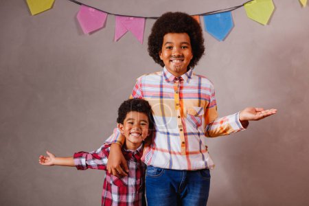 Téléchargez les photos : Enfants en vêtements typiques de la célèbre fête brésilienne appelée "Festa Junina" pour célébrer So Joo. Afro garçons et fille blanche célébrant la fête de Juin au Brésil - en image libre de droit
