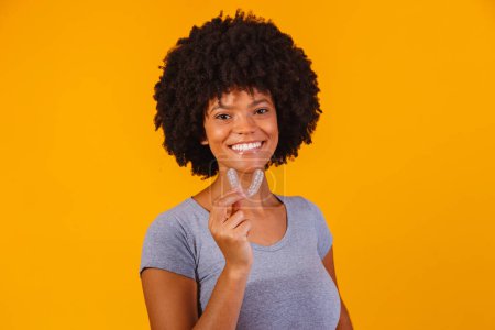 Téléchargez les photos : Afro femme tenant plaque de blanchiment. Dispositif invisible. - en image libre de droit