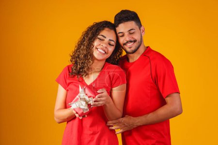 Téléchargez les photos : Portrait d'un beau couple sur fond jaune avec un cadeau - en image libre de droit