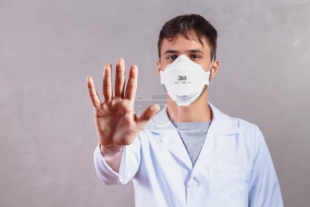 Photo for Young man UK ICU doctor hand gesturing STOP Coronavirus COVID-19 disease global pandemic outbreak,please help not spread virus worldwide,stay safe home keep social physical distance isolation - Royalty Free Image
