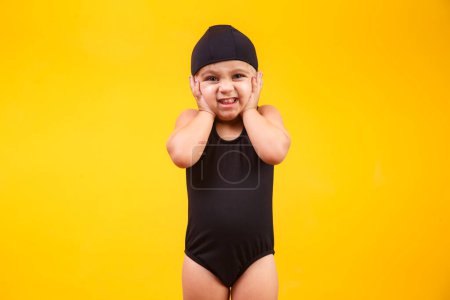 Téléchargez les photos : Petite fille en tenue de plage sur fond jaune. Concept d'été et vacances - en image libre de droit