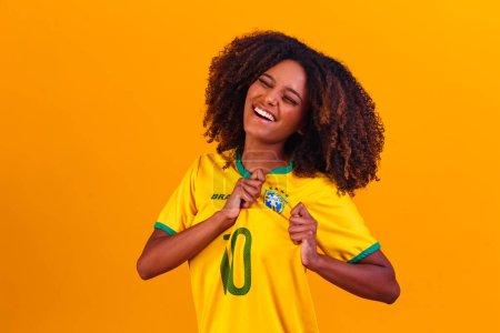 Téléchargez les photos : Un partisan brésilien. Fan brésilien femme célébrant sur le football ou match de football sur fond jaune. Couleurs Brésil. - en image libre de droit