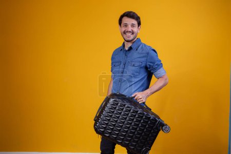 Téléchargez les photos : Homme heureux tenant valise souriant regardant la caméra - en image libre de droit