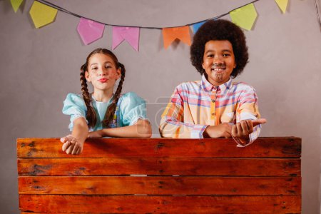 Photo for Children in typical clothes from the famous Brazilian party called "Festa Junina" in celebration of So Joo. Afro boy and white girl celebrating the June party in Brazil - Royalty Free Image