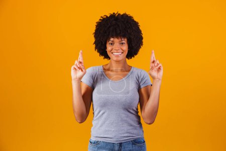 Téléchargez les photos : Afro femme avec les doigts croisés acclamant victoire - en image libre de droit