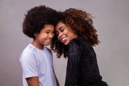 Foto de Retrato de una joven madre afroamericana con un hijo pequeño. Fondo gris. Familia brasileña. - Imagen libre de derechos