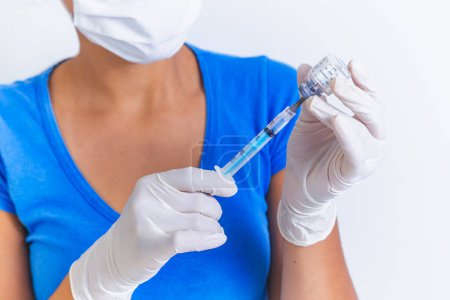 Téléchargez les photos : Vaccin COVID-19 entre les mains d'un chercheur, une femme médecin tient une seringue et un flacon avec un vaccin pour guérir le coronavirus. Concept de traitement du virus corona, injection, injection et essai clinique pendant la pandémie. - en image libre de droit