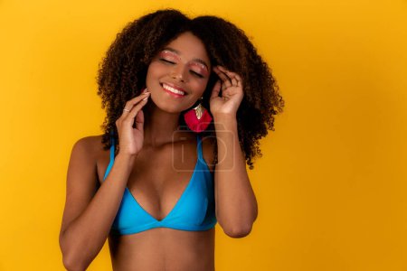Téléchargez les photos : Belle afro girl aux cheveux bouclés et au bikini sourire à la caméra - en image libre de droit