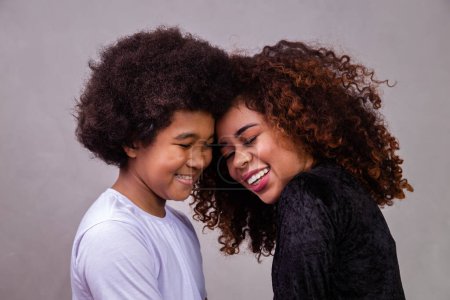 Foto de Retrato de una joven madre afroamericana con un hijo pequeño. Fondo gris. Familia brasileña. - Imagen libre de derechos