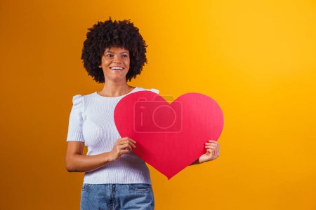 Téléchargez les photos : Portrait photo d'une femme afro souriante tenant un grand carton rouge - en image libre de droit