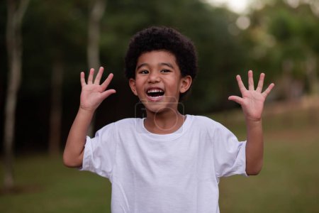 Téléchargez les photos : Petit afro garçon grimacing montrant les mains à la caméra - en image libre de droit