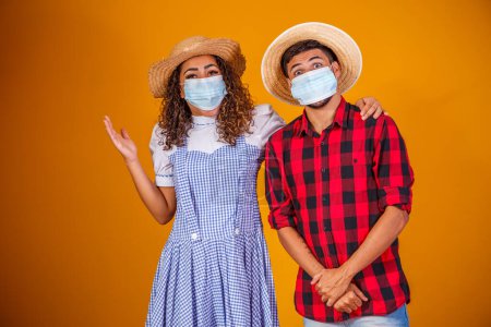 Téléchargez les photos : Couple portant des vêtements typiques pour la Festa Junina (Junina Party) et un masque de protection pour prévenir COVID-19. - en image libre de droit