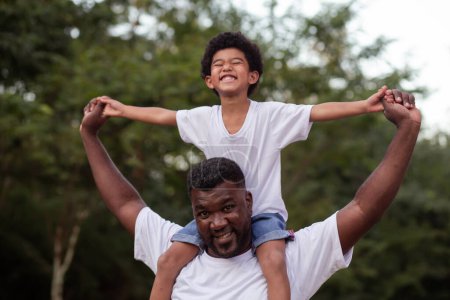 Foto de Afro chico con su padre en el parque en su cuello - Imagen libre de derechos
