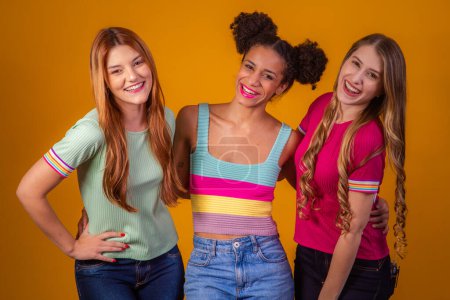 Photo for Happy girlfriends on yellow background in diversity. Redhead, afro and blonde on yellow background. diversity concept - Royalty Free Image