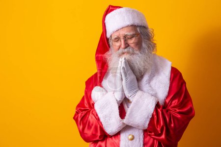 Photo for Santa Claus praying on yellow background. Faith - Royalty Free Image