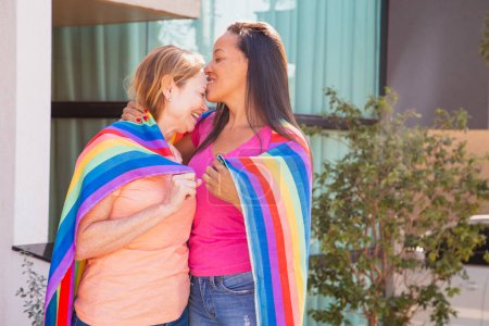 Téléchargez les photos : Couple lesbien avec drapeau lgbt. Femme embrassant sa femme sur le front. Saint Valentin - en image libre de droit