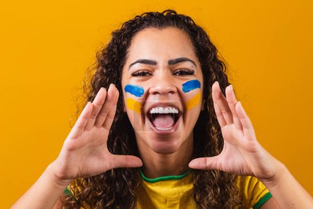 Photo for Brazilian fan with her face painted in blue and yellow for the brazil game. Brazilian celebrating the independence of Brazil. September 7th. Brazilian fan screaming with happiness - Royalty Free Image