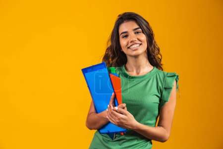 Photo for Smiling woman student with school books in hands on yellow background. - Royalty Free Image
