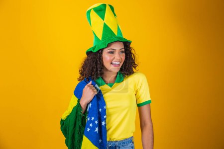 Foto de Apoyador de Brasil. Brasileña rizado pelo mujer fan celebrando en el fútbol, partido de fútbol sobre fondo amarillo. Brasil colores. - Imagen libre de derechos