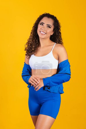 Photo for Beautiful young afro woman in fitness outfit smiling looking at camera with space for text. Vertical - Royalty Free Image