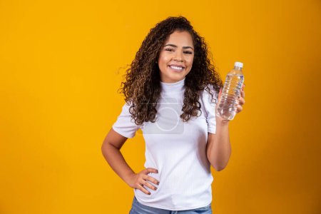 Téléchargez les photos : Femme tenant une bouteille d'eau sur fond jaune. Boire de l'eau! - en image libre de droit