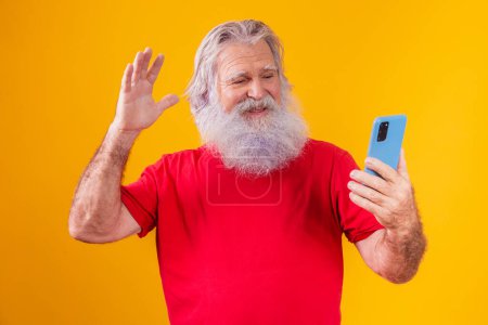 Photo for Cheerful elderly man holding a smartphone, having video call online, chatting with grown children, communicating with a friend at a distance, older generation modern technology comfortable user-friendly concept. - Royalty Free Image