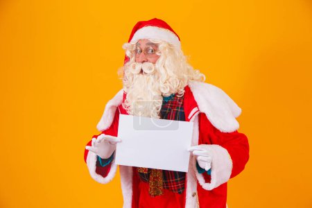 Photo for Santa Claus with a white banner with space for text. Santa Claus holding a white card - Royalty Free Image