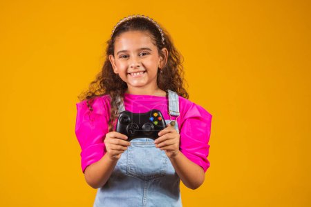Photo for Little girl playing video game on yellow background. - Royalty Free Image