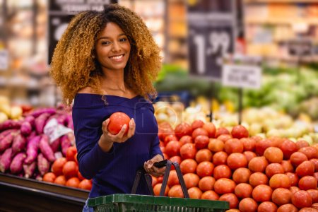 Photo for Young afro selecting tomatoes in the market - Royalty Free Image