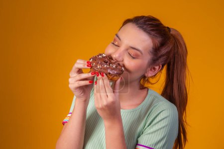 Photo for Young red-haired woman eating delicious chocolate donuts. Young man enjoying a tasty donuts - Royalty Free Image