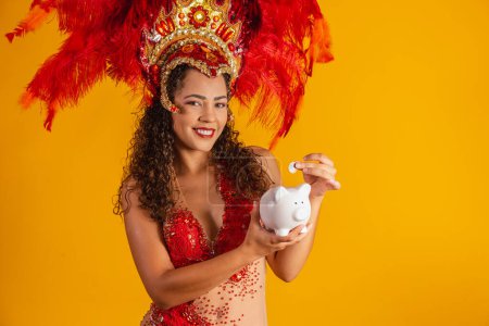 Photo for Carnival dancer woman holding a piggy bank in hands. Concept of saving for carnival - Royalty Free Image