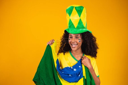 Photo for Brazilian supporter. Brazilian woman fan celebrating on soccer or football match on yellow background. Brazil colors. - Royalty Free Image