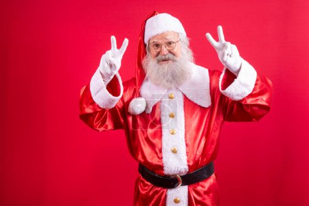 Photo for Santa Claus looking at the camera. Christmas is coming. Merry Christmas. Peace. V sign. - Royalty Free Image