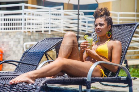 Téléchargez les photos : Jeune femme en vacances à la piscine de l'hôtel prenant une délicieuse boisson alcoolisée. - en image libre de droit