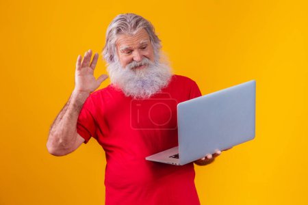 Foto de Anciano sobre fondo amarillo haciendo una videollamada en el portátil. - Imagen libre de derechos