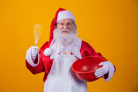 Photo for Santa Claus with a bowl beating cake on yellow background - Royalty Free Image